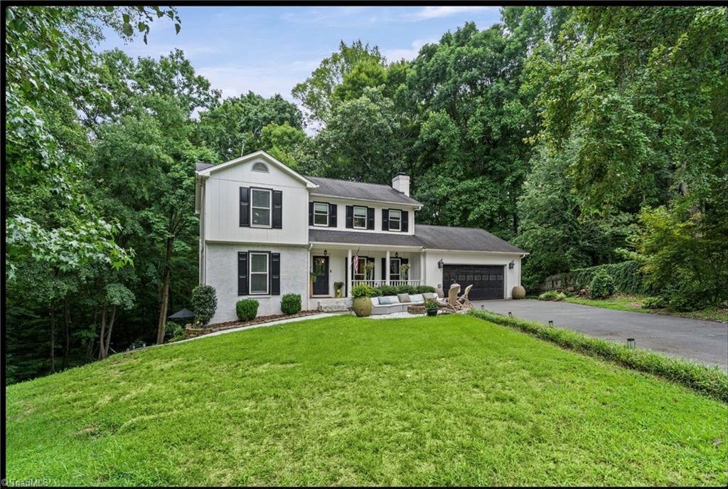 1450 Old Coach Road Kernersville NC front exterior — white two-story colonial home with dark shutters, front porch, and wooded cul-de-sac lot