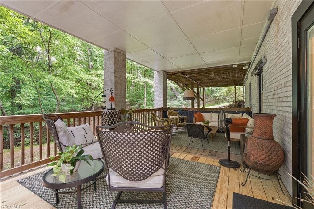 1450 Old Coach Road Kernersville NC private covered deck — outdoor living space with wooded views, brick columns, and wood-plank ceiling adjoining the ADU walk-out entrance